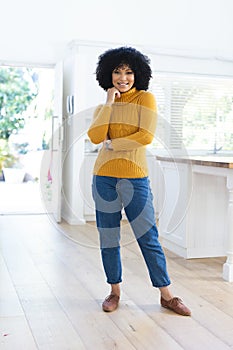 Happy african american woman standing with hand on face at home, copy space