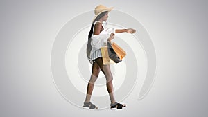 Happy african american woman in straw hat walking with shopping