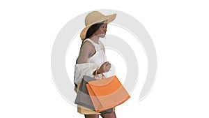 Happy african american woman in straw hat walking with shopping bags on white background.