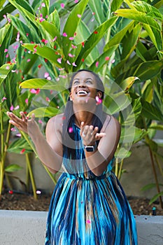 Happy African American Woman Tosses Flower Petals Into The Air photo