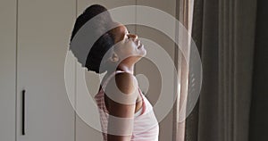 Happy african american woman widening curtains in bedroom