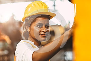 Happy African American woman worker with safety suit helmet enjoy smiling working as labor in heavy industry factory with steel