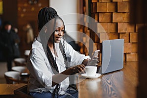 Happy african american woman worker using laptop work study at computer in loft office or cafe, smiling mixed race female student