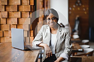 Happy african american woman worker using laptop work study at computer in loft office or cafe, smiling mixed race female student