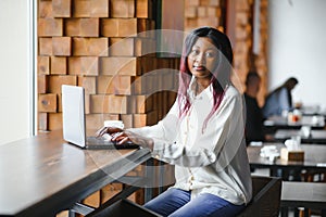 Happy african american woman worker using laptop work study at computer in loft office or cafe, smiling mixed race female student