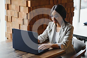 Happy african american woman worker using laptop work study at computer in loft office or cafe, smiling mixed race female student