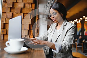 Happy african american woman worker using laptop work study at computer in loft office or cafe, smiling mixed race female student