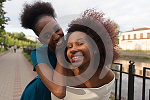 Happy African American women cuddle, friends