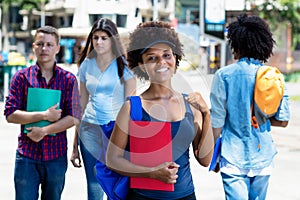 Happy african american young adult woman with students in city