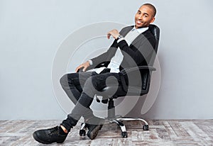 Happy african american young man sitting in leather office chair