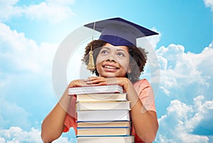 Happy african bachelor girl with books over sky