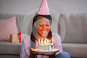 Happy african birthday woman holding festive cake with lightened candles