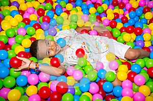 Happy african black boy playing in ball pit on birthday party in kids amusement park and indoor play center. Child