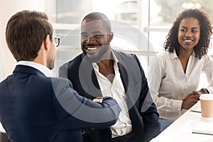 Happy african businessman handshake reliable male partner at team meeting