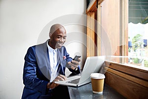 Happy african businessman using phone at cafe