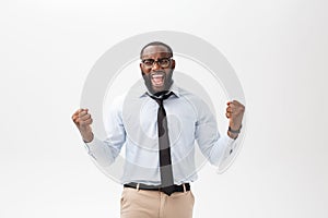 Happy african businessman wearing a corporate grey shirt and black tie punching the air with his fists arms in air