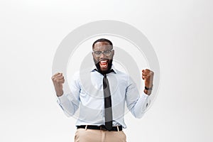 Happy african businessman wearing a corporate grey shirt and black tie punching the air with his fists arms in air