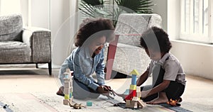 Happy african children playing toys sit on floor at home