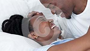 Happy African couple in bed, talk and smile have silly conversation in morning on holiday or at their house. Black woman