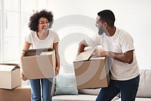 Happy African Couple Carrying Packed Moving Boxes Entering New Home