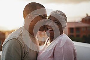 Happy african couple having tender moment outdoors at summer sunset - Focus on woman face