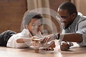 Happy african dad and child boy play with toy plane