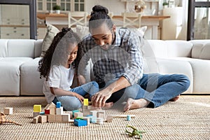 Happy African dad and daughter girl completing construction model