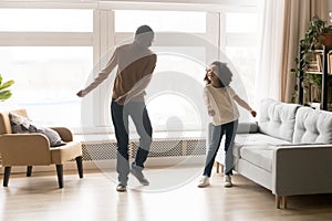 Happy african dad and kid daughter dancing in living room