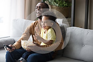 Happy african dad and kid son laughing watching funny comedy