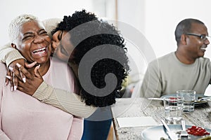 Happy african daughter having tender moment during lunch at home - Main focus on mother face