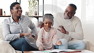 Happy african family afro american parents helping black little girl schoolgirl child draw picture homework sitting on