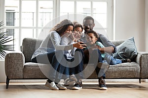 Happy african family with 2 children having fun with gadget photo