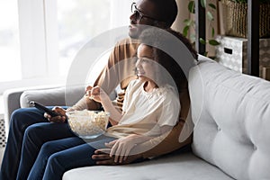 Happy african family dad with child daughter watching tv together