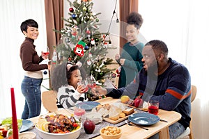 Happy African family eating food in dinner on festive thanksgiving eve day together at home.