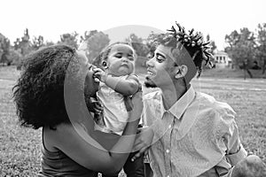 Happy African family enjoying a tender moment during the weekend outdoor - Mother and father having fun with their daughter