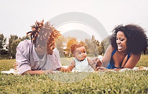 Happy African family enjoying together a weekend sunny day outdoor - Mother and father having fun with their daughter