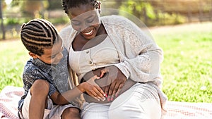 Happy African family expecting other baby - Afro Mother and son touching pregnant belly doing heart shape with hands