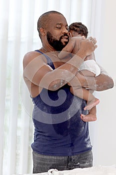 Happy African family, Father holding cute toddle baby infant kid after taking a bath and apply talcum powder on body ready in