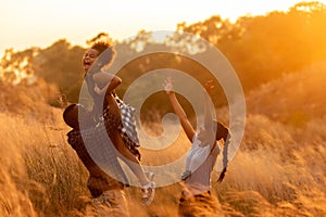 Happy African family father mother and child daughter travel and running on meadow nature on silhouette lights sunset.