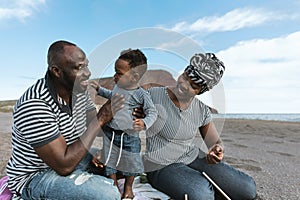 Happy African family having fun on the beach during summer holidays