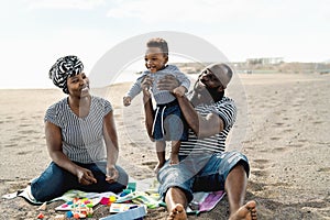 Happy African family having fun on the beach during summer holidays - Parents love concept