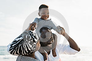 Happy African family having fun on the beach during summer holidays - Parents love concept