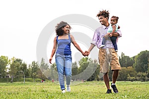 Happy African family having fun in public park - Mother and father with their daughter enjoying time together