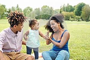 Happy African family having fun in public park - Mother and father with their daughter enjoying time together during weekend