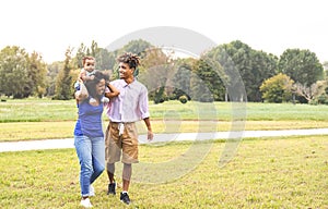 Happy African family having fun in public park - Mother and father with their daughter enjoying together during weekend sunny day