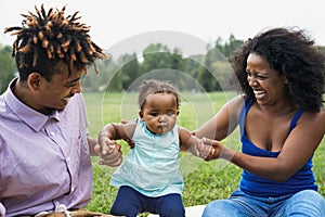 Happy African family having fun together in public park - Black father and mother enjoying time with their daughter