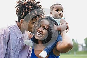 Happy African family having fun together in public park - Black father and mother enjoying weekend with their daughter