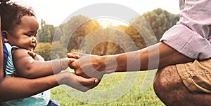 Happy African family having fun together in public park - Black father and mother holding hand with their daughter