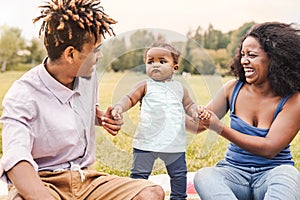 Happy African family having fun together in public park - Black mother father and baby daughter enjoying lovely time outdoor