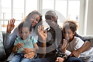 Happy african family with kids waving hands looking at camera